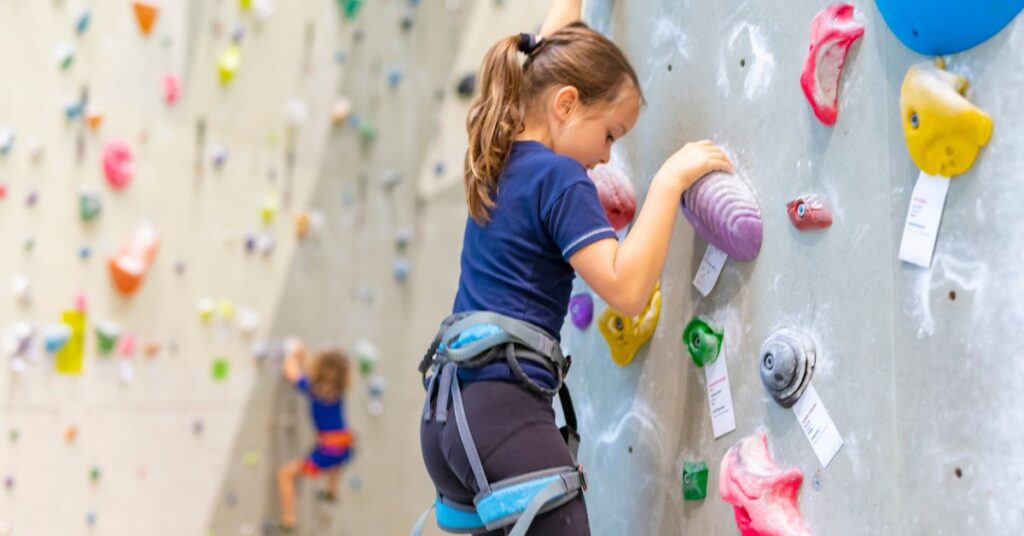 Girl on a rock climbing wall. How can you encourage your child with autism and ADHD to try new activities?