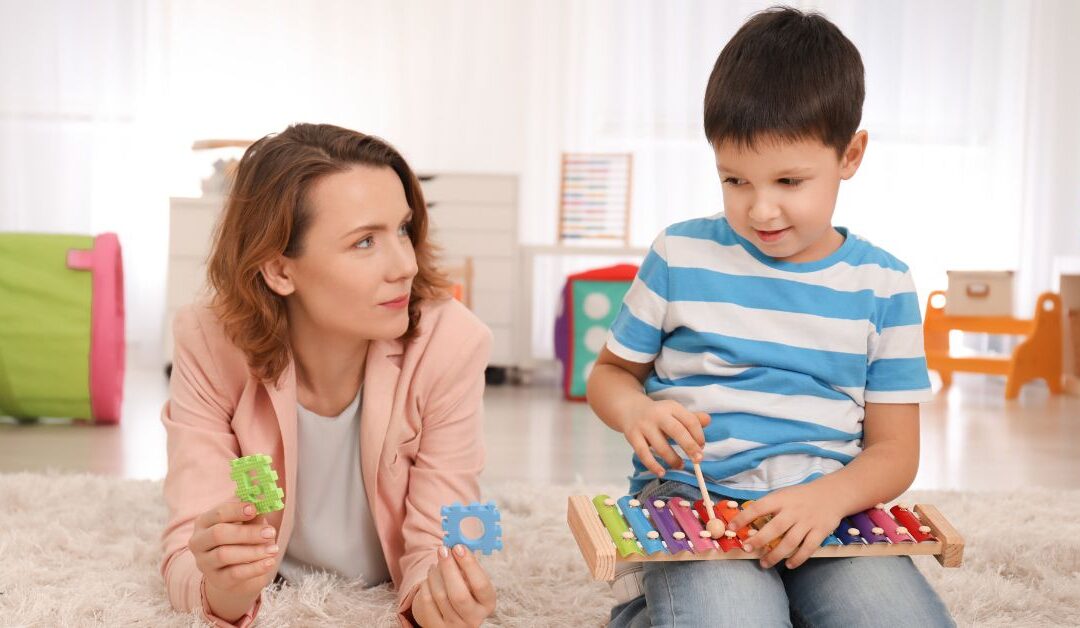 Mom on the floor with puzzle pieces lying next to son playing xylophone