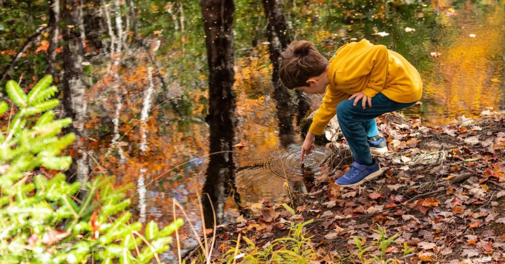 Boy inspecting water on a hike. Reasons why nature outings are good for your autistic child.