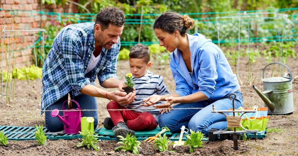 Parents sitting with little boy planting in a garden. How nature outings benefit your autistic child.