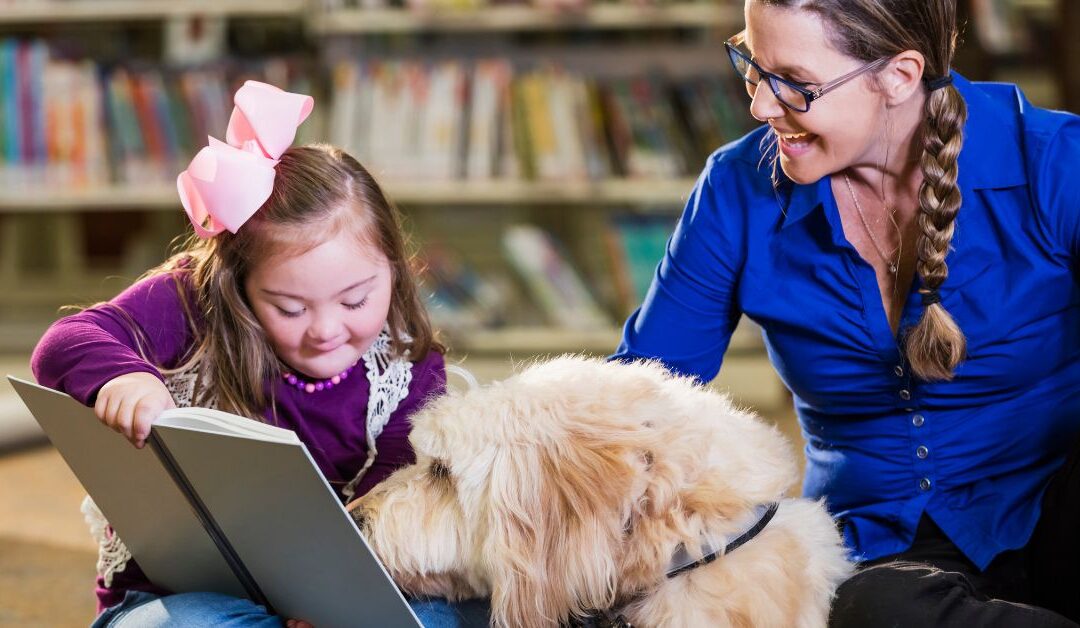 Girl with Down Syndrome sitting with dog and teacher