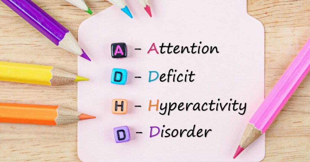 ADHD spelled out with letters on colored dice and colored pencils set on the side of paper