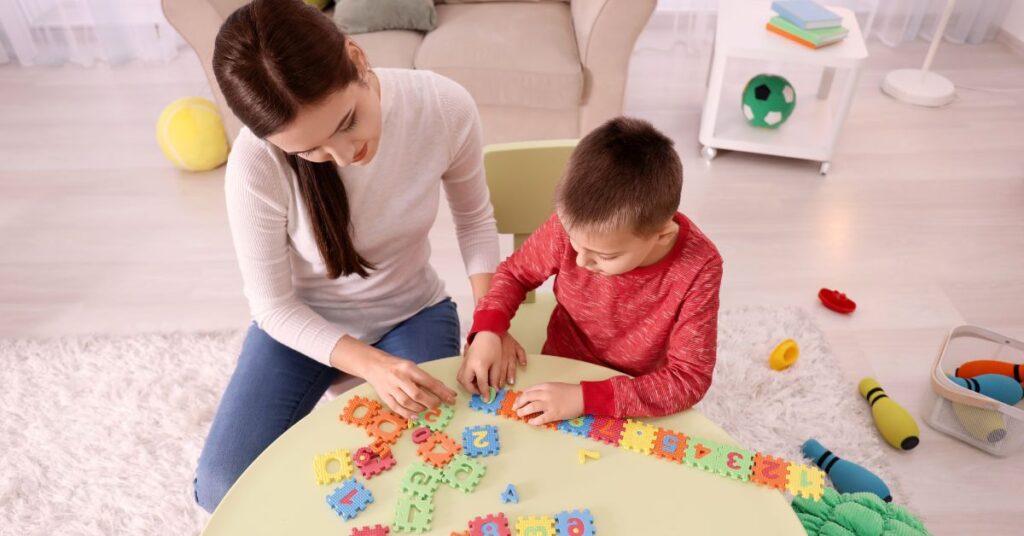 Childcare provider doing a puzzle with a little boy at a table