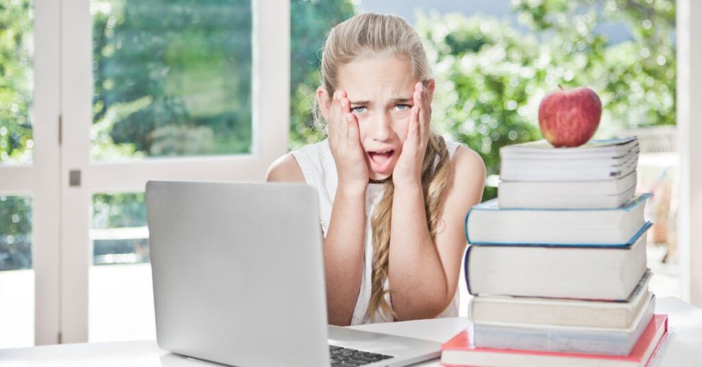 Girl sitting among books holding her face with a dismayed expression. How you can help your autistic ADHD child improve their working memory.