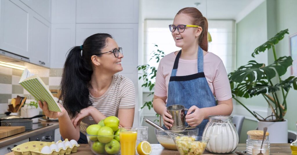 Teenage girl learning to cook from her mom. Learn how to teach independent skills with "Advocating for Your Autistic Child" e-book.