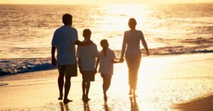 Family of four walking together on the beach. Be inspired by autism, ADHD and parenting quotes.
