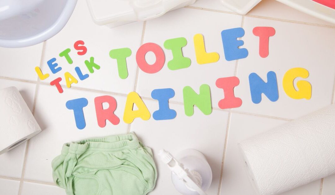Let's Talk Toilet Training written on floor with toilet training accessories around it