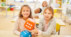 Two girls holding big dice and smiling