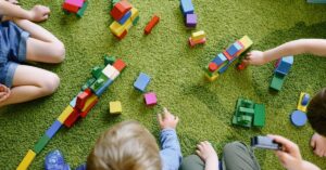 Blocks with kids' arms and legs shown playing with them. How can holiday camp benefit your child with autism and ADHD?
