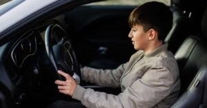Teen boy sitting in driver seat in a car. How can you keep your teen with autism and ADHD safe while driving?