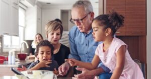 Grandparents cooking with two grandchildren. How can you deal with family or friends who reject your child's autism diagnosis?