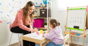 Therapist working with an autistic girl. How a Picture Exchange Communication System can help your autistic child better communicate.