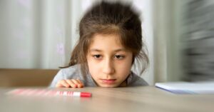 Little girl staring at a marker while resting her head on a table. How do you use the autism levels to better understand where your child fits on the autism spectrum disorder?