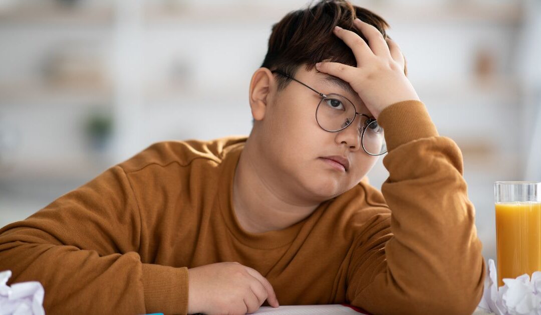 Boy working on homework with hand on head in frustration