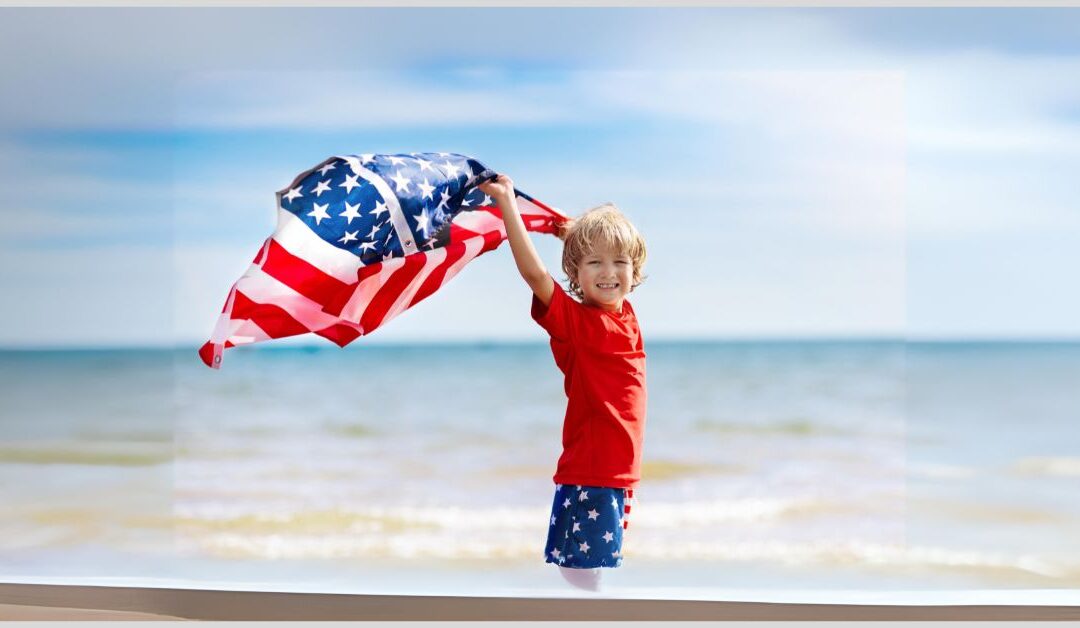 Boy standing on beach holding an American flag