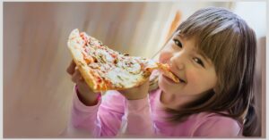 Girl eating a big slice of pizza. Are there foods your child should avoid to reduce triggering ADHD symptoms?