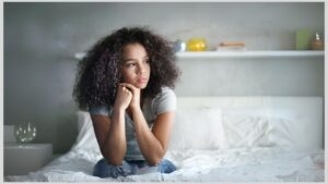 Teenage girl sitting on bed looking sad. How to help your autistic child if they are masking.