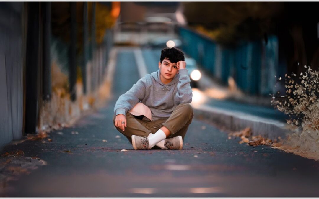 Teenage boy sitting on road. How to support your autistic teenager through the adolescent years