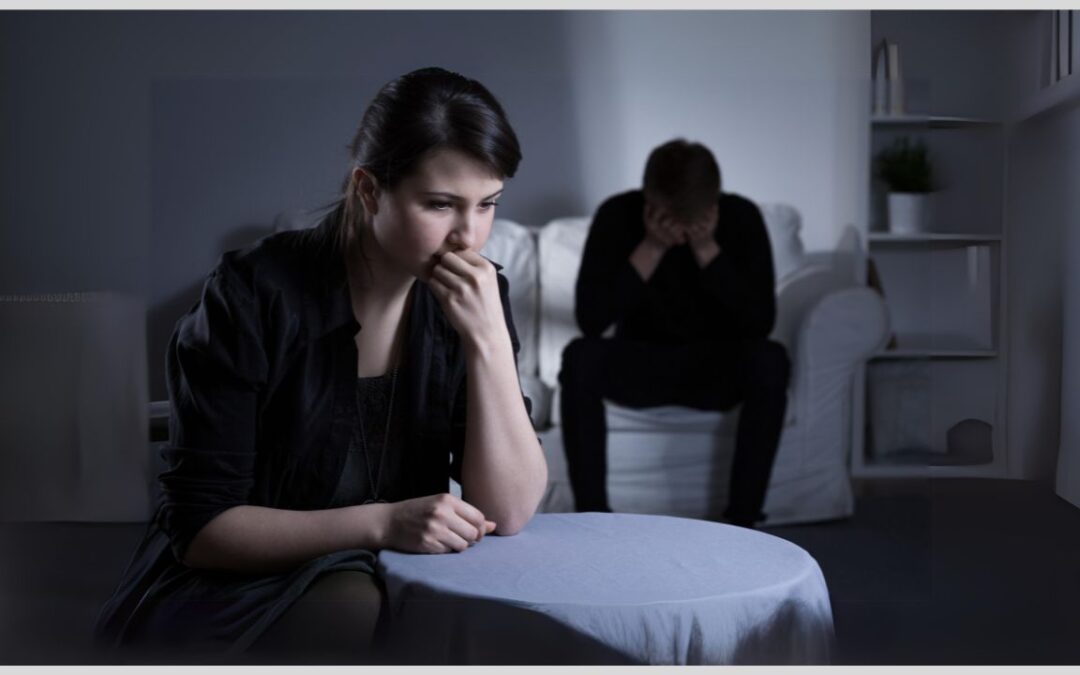 Couple sitting separately on couch and at table