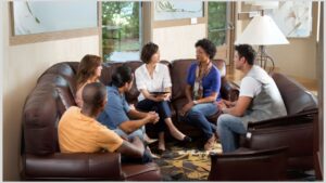 Group of parents sitting in a living room talking to each other. It's important to have solidarity with other parents of autistic/ADHD children