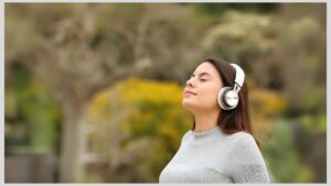 Teenage girl standing outside with eyes closed and headphones on